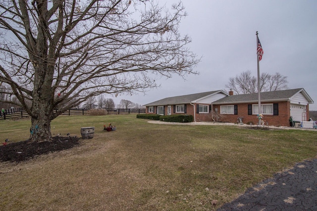 view of front facade with brick siding, a chimney, an attached garage, fence, and a front lawn