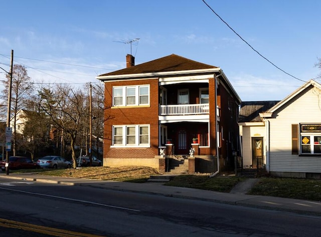 view of front of home with a chimney and a balcony