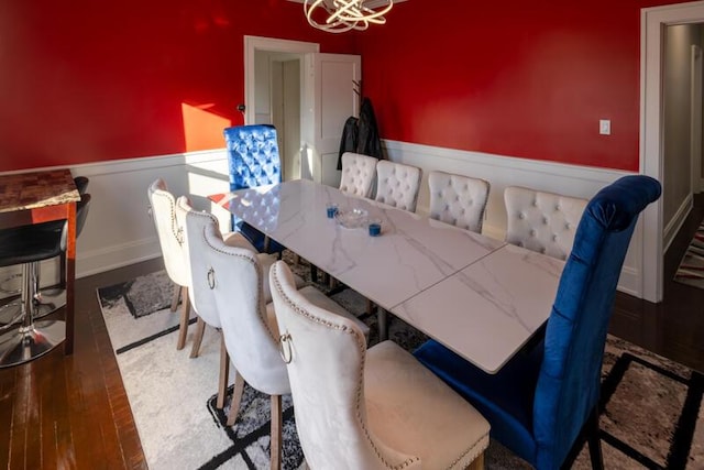 dining space with an inviting chandelier, wood finished floors, and wainscoting