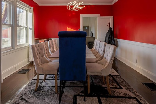 dining area featuring visible vents, ornamental molding, wood finished floors, wainscoting, and a chandelier