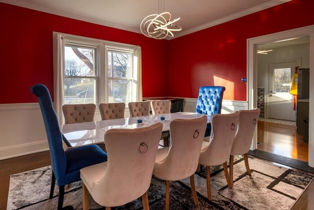 dining room featuring crown molding, wood finished floors, a wainscoted wall, and a chandelier