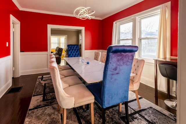 dining space featuring wood finished floors, a chandelier, and wainscoting