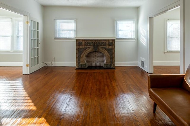 unfurnished living room featuring hardwood / wood-style floors, baseboards, and a wealth of natural light