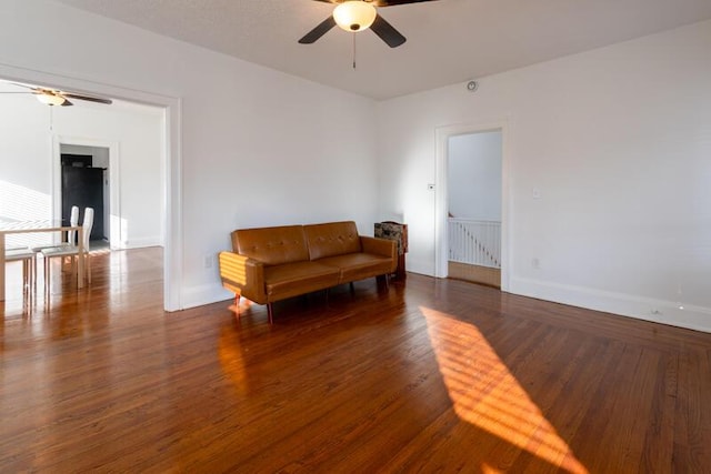 living area featuring wood finished floors, a ceiling fan, and baseboards