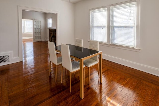 dining room with visible vents, baseboards, wood finished floors, and a fireplace