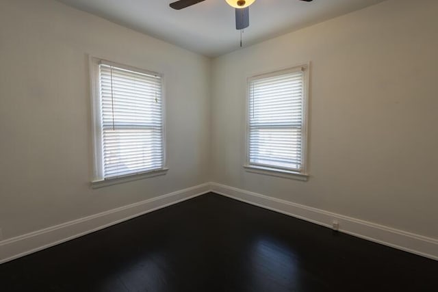 unfurnished room featuring dark wood finished floors, a ceiling fan, baseboards, and a healthy amount of sunlight