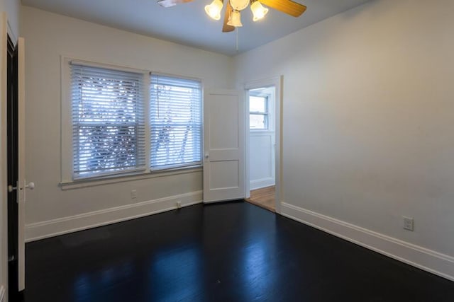 unfurnished room with dark wood-style floors, baseboards, and ceiling fan