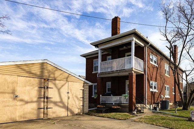 rear view of property featuring a balcony, cooling unit, a porch, a chimney, and a garage