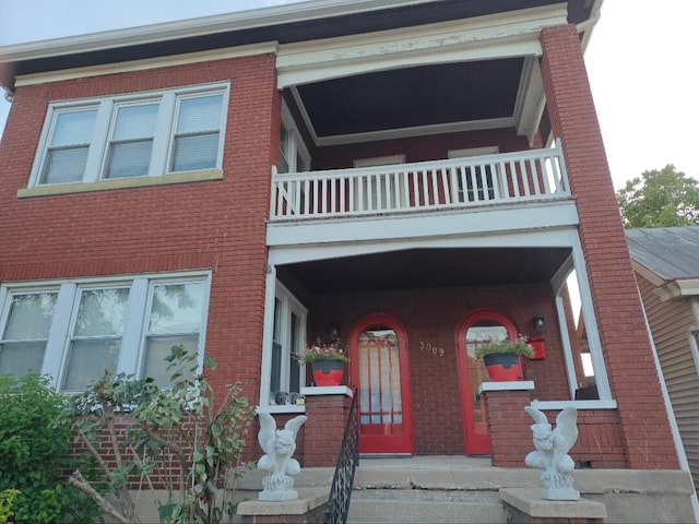 view of front facade with brick siding and a balcony