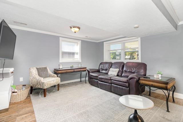 living area with visible vents, ornamental molding, light wood-type flooring, and a wealth of natural light