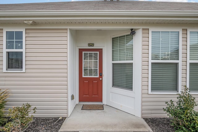 doorway to property featuring roof with shingles