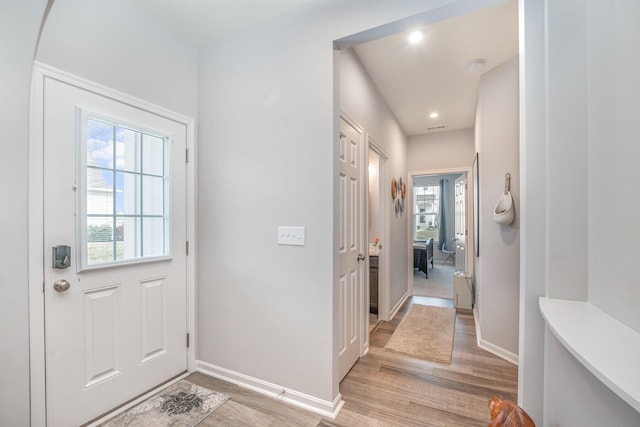 doorway featuring plenty of natural light, recessed lighting, light wood-type flooring, and baseboards