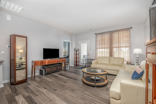 living room with baseboards, visible vents, and wood finished floors