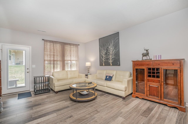 living room featuring visible vents, plenty of natural light, and light wood-style flooring