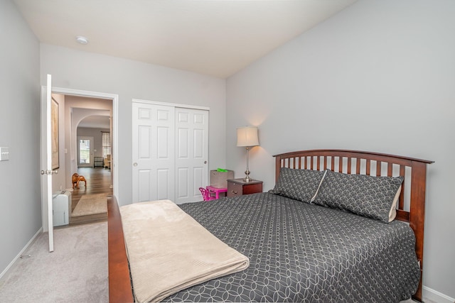 bedroom featuring carpet floors, baseboards, arched walkways, and a closet