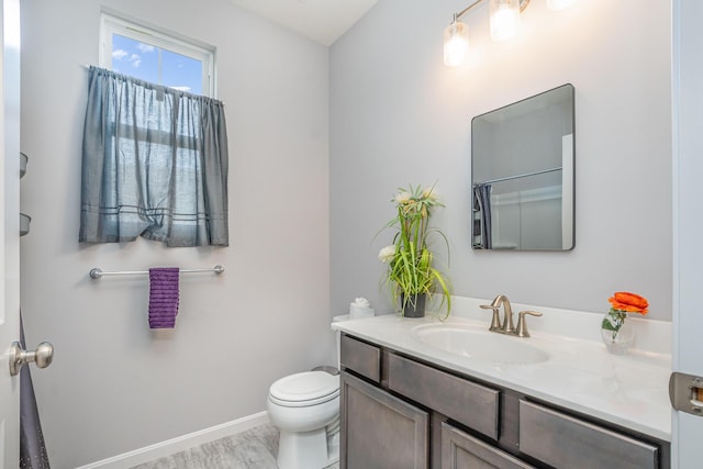 bathroom featuring baseboards, vanity, and toilet