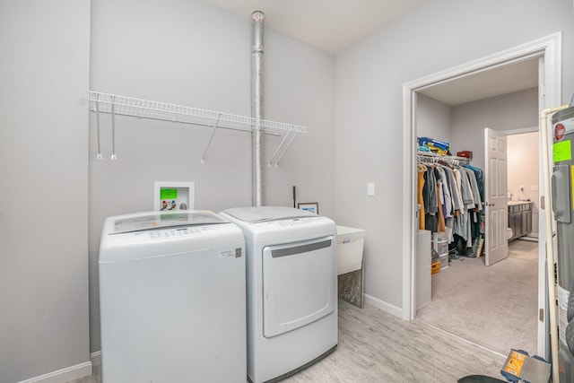 clothes washing area featuring light wood-type flooring, laundry area, baseboards, and separate washer and dryer