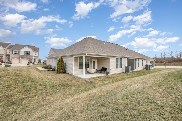 rear view of property featuring a shingled roof, a yard, a patio, and central air condition unit