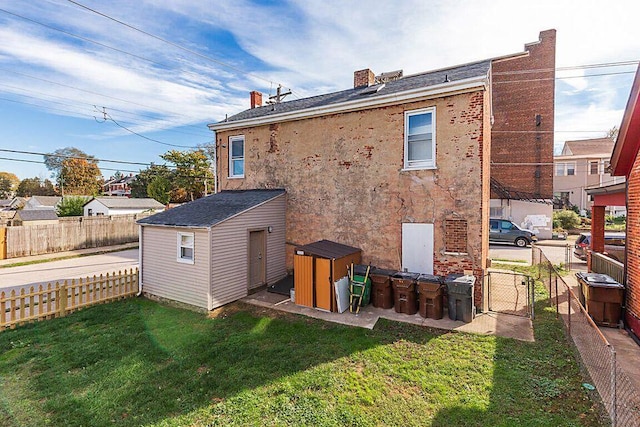 rear view of property featuring an outbuilding, a yard, a gate, fence, and a shed