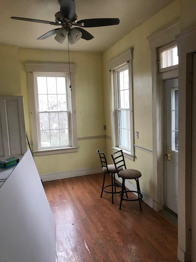 living area featuring wood finished floors, a ceiling fan, and baseboards