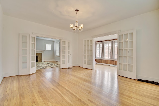 empty room with french doors, a healthy amount of sunlight, and light wood-style flooring