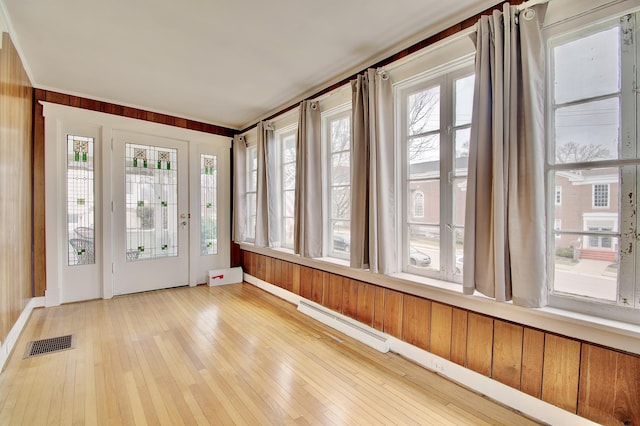 unfurnished sunroom with a baseboard heating unit, a healthy amount of sunlight, and visible vents