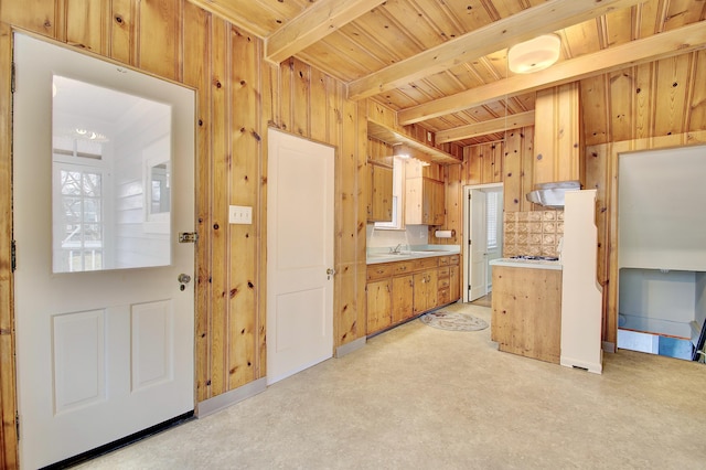 kitchen with light countertops, a healthy amount of sunlight, wood walls, beamed ceiling, and under cabinet range hood