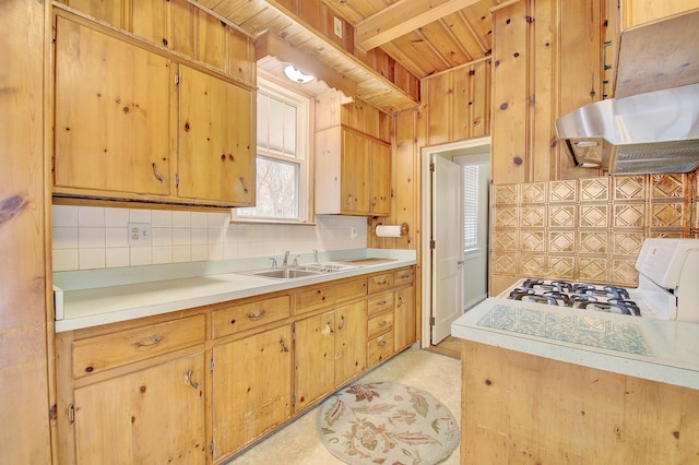 kitchen with decorative backsplash, gas range gas stove, light countertops, under cabinet range hood, and a sink