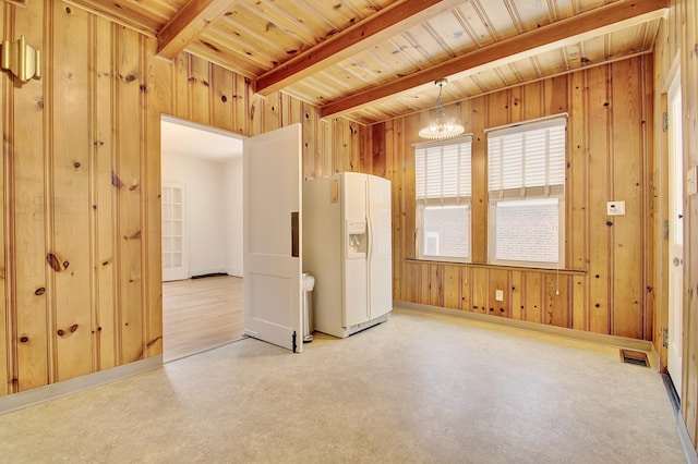 spare room with wood walls, concrete floors, beam ceiling, and visible vents