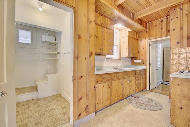 kitchen with tasteful backsplash, wood ceiling, beam ceiling, light countertops, and a sink