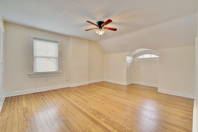 empty room with vaulted ceiling, light wood-style flooring, baseboards, and ceiling fan