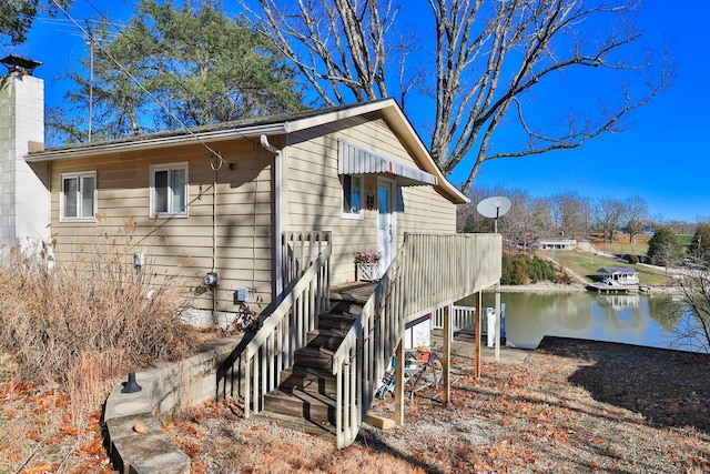 view of side of property featuring stairs, a chimney, and a water view