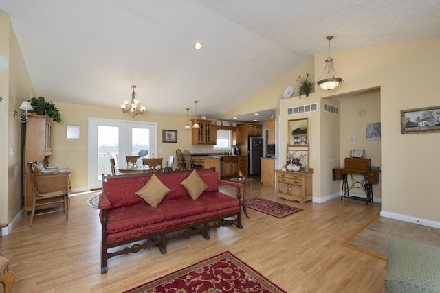 living area with light wood-style floors, visible vents, and vaulted ceiling