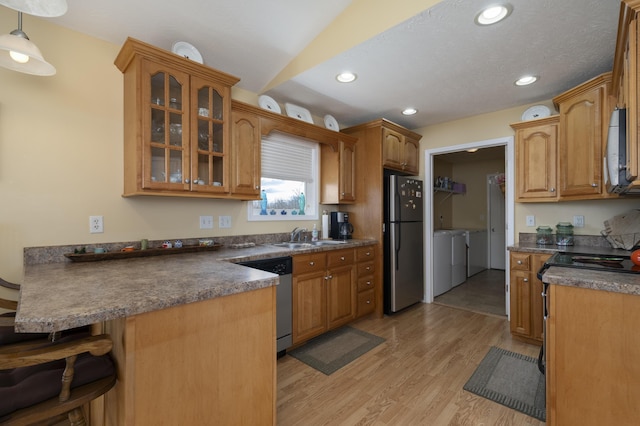 kitchen with washer and clothes dryer, glass insert cabinets, appliances with stainless steel finishes, a peninsula, and a sink