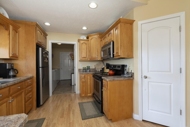 kitchen with a textured ceiling, recessed lighting, stainless steel appliances, light wood-type flooring, and washer and clothes dryer