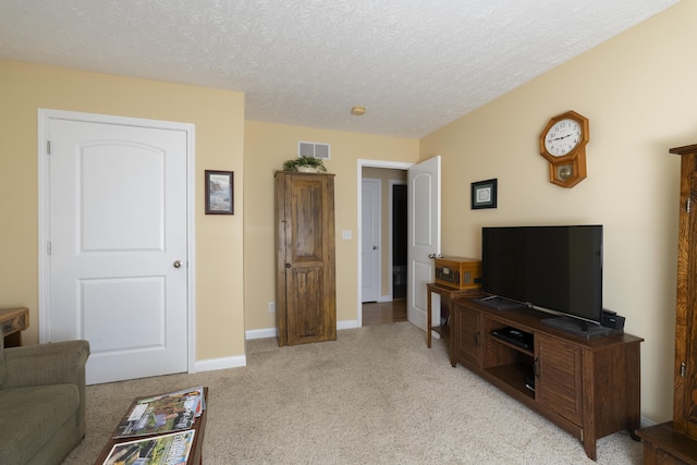 living room featuring baseboards, visible vents, a textured ceiling, and light colored carpet