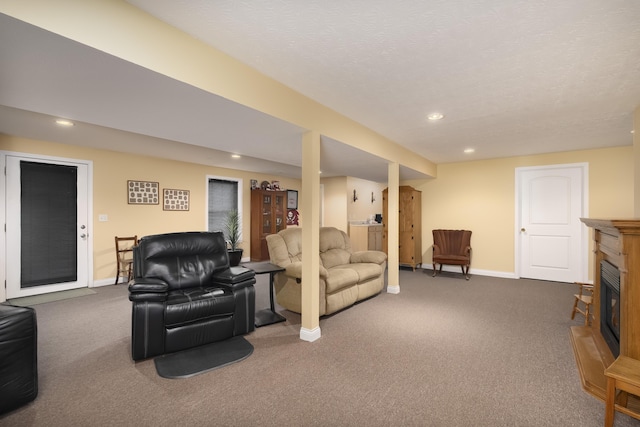 carpeted living area with baseboards, a textured ceiling, a glass covered fireplace, and recessed lighting