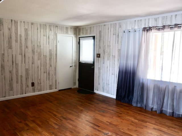 empty room with plenty of natural light, baseboards, and wood finished floors