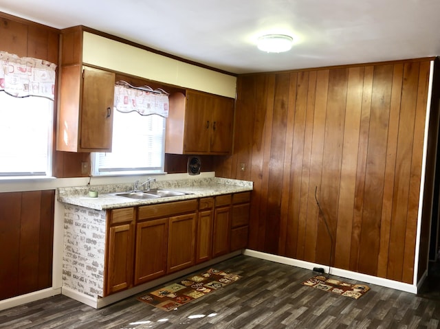 kitchen with wooden walls, dark wood-type flooring, a sink, light countertops, and brown cabinets