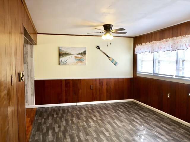 unfurnished room with ornamental molding, wood walls, wood finished floors, and a ceiling fan