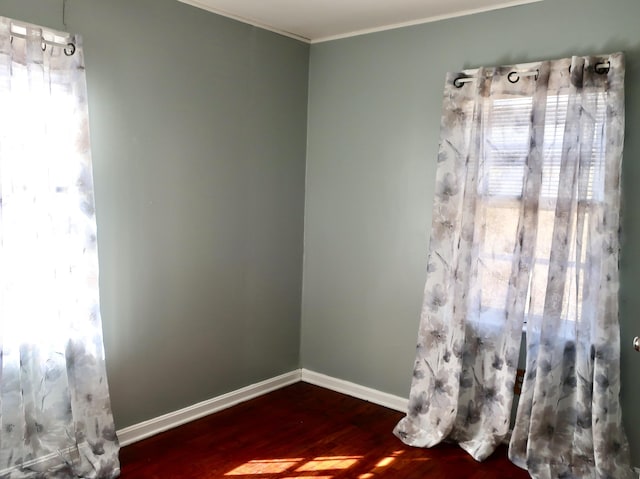 unfurnished room with crown molding, dark wood-type flooring, and baseboards