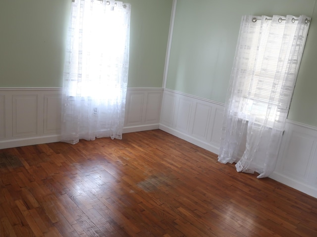 empty room featuring a wainscoted wall, wood finished floors, and a decorative wall