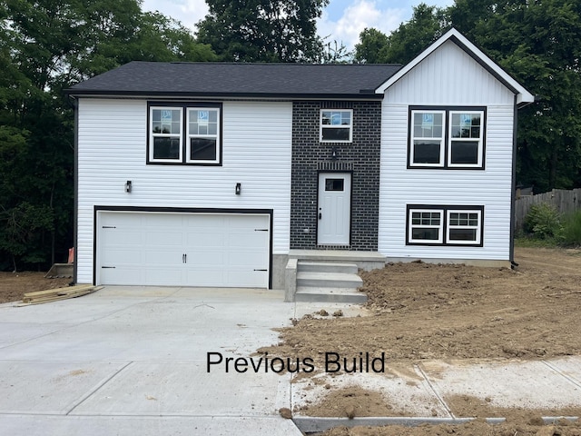 raised ranch with a garage, driveway, and board and batten siding