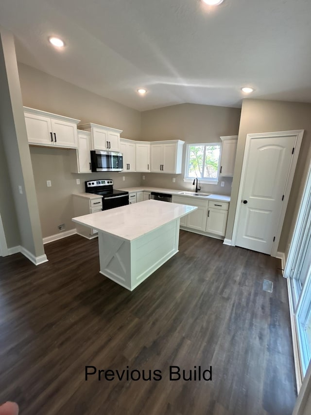 kitchen with a sink, light countertops, appliances with stainless steel finishes, a center island, and dark wood finished floors