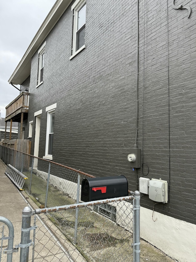 view of property exterior featuring fence and brick siding