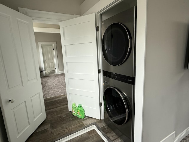 laundry room featuring baseboards, laundry area, dark wood-type flooring, and stacked washer / drying machine