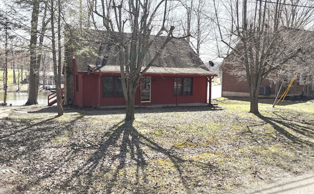 rear view of property featuring a water view and roof with shingles