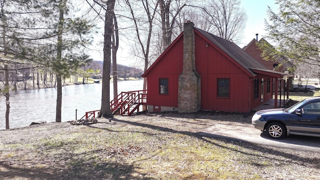 view of side of property featuring a chimney, roof with shingles, and a water view