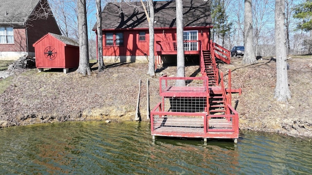 exterior space featuring a storage unit, stairs, an outdoor structure, and a water view