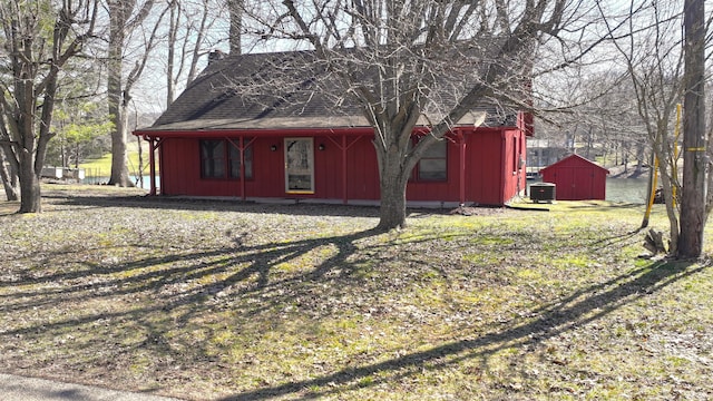 exterior space featuring central air condition unit, an outbuilding, a shed, board and batten siding, and roof with shingles